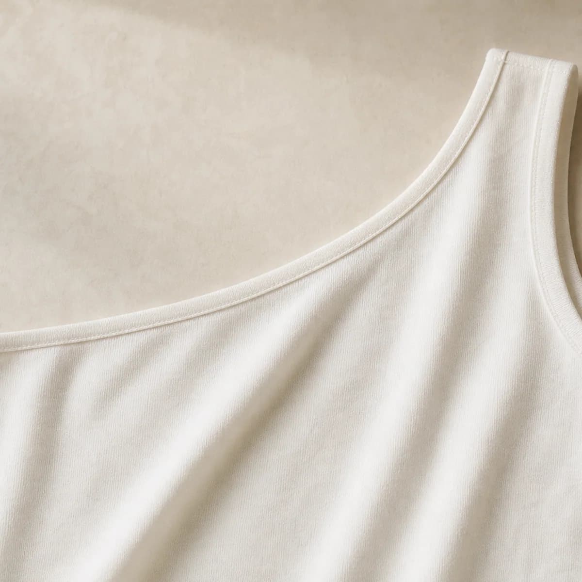 Fabric and neckline detail of the white one-shoulder top